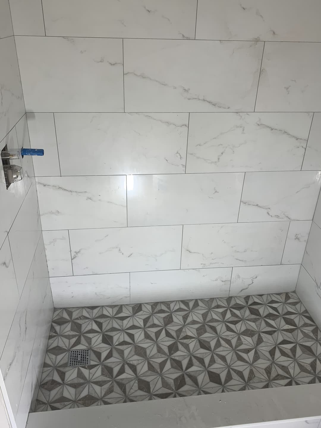 picture of a bathroom being remodeled with pattern tile flooring and marble walls