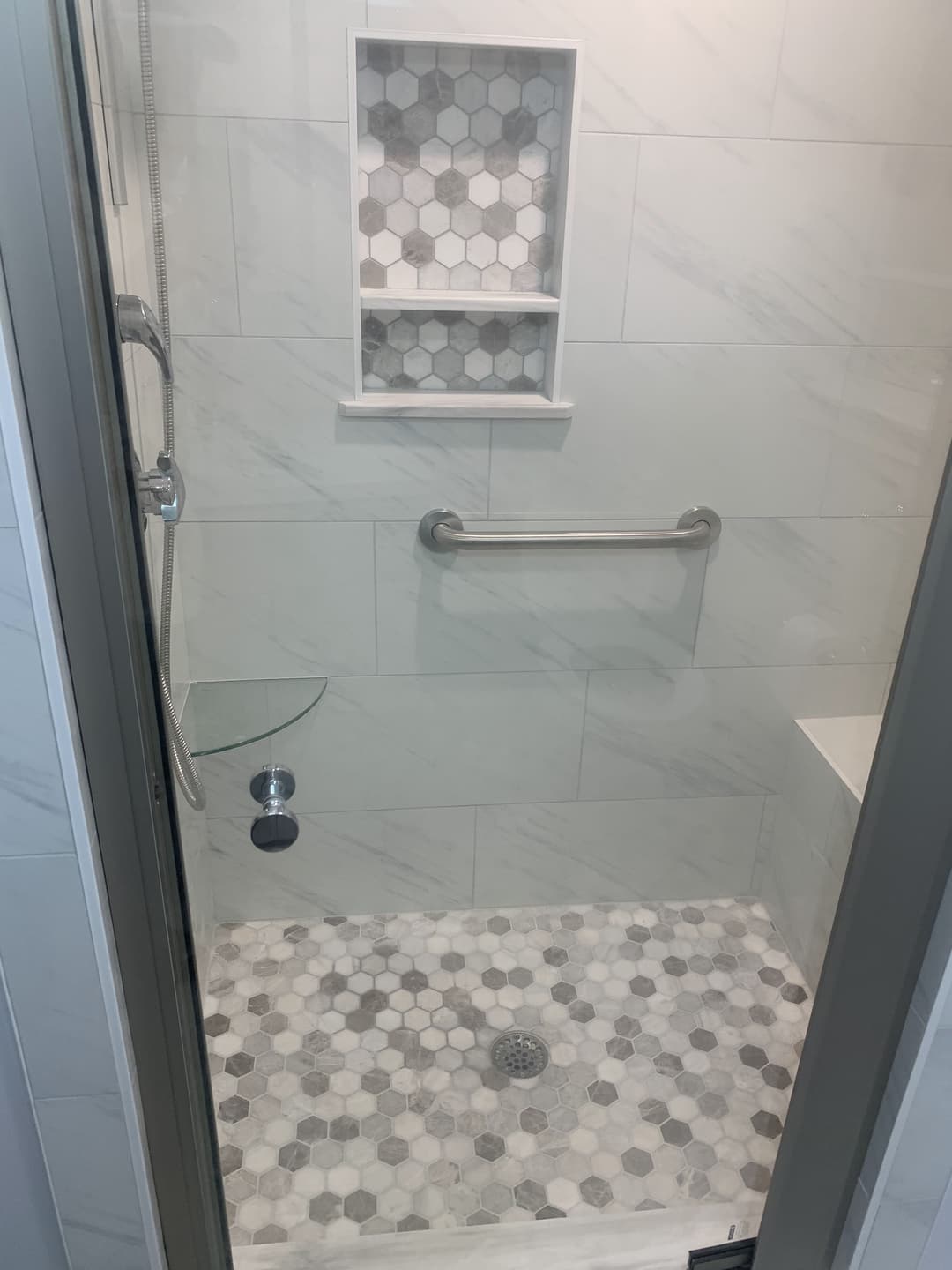 newly remodeled shower with textured tile pattern fooring